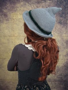 a woman with long red hair wearing a gray crochet hat and black dress