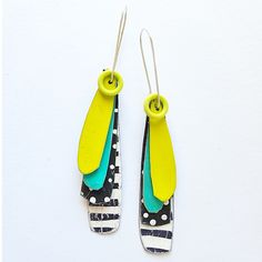 two pairs of earrings with yellow and blue designs on them, hanging from metal hooks