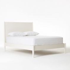 a bed with white sheets and pillows on it's headboard, against a white background