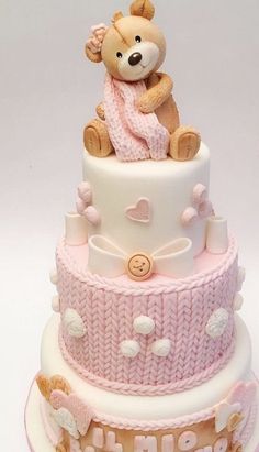 a three tiered cake with a teddy bear on top