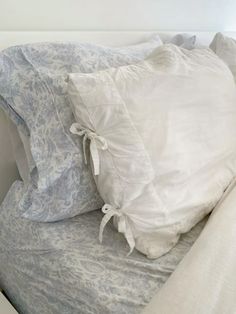 two pillows on top of a bed with white linens and blue floral print sheets