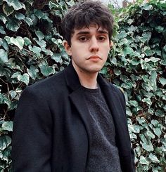 a young man standing in front of a bush