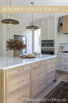 a large kitchen with white cabinets and gold lights hanging from the ceiling, along with an area rug on the floor