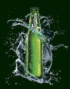 a green bottle with water splashing around it