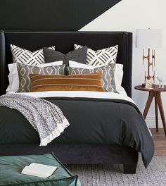 a bed with black headboard and pillows on it