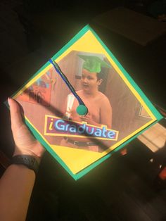 a person holding up a kite with the image of a young boy on it's side