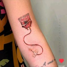 a woman's arm with a coca cola tattoo on it