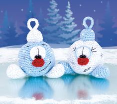 two crocheted stuffed animals sitting on top of snow covered ground with trees in the background