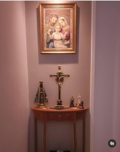 a small wooden table with figurines and a painting on the wall above it