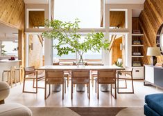 a dining room table and chairs in front of a large window with wooden paneling