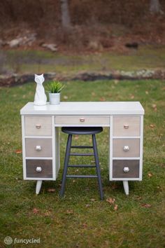 a white desk with drawers and a plant on it in front of a grassy area