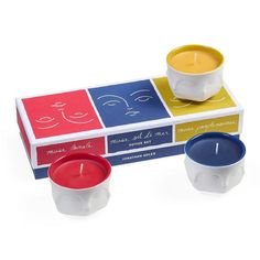 three candles sitting on top of each other in front of a box with four different designs