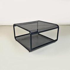 a black metal table sitting on top of a white floor in front of a wall