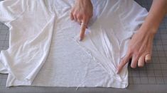 a person is cutting fabric with scissors on the floor next to a piece of cloth