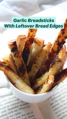 garlic breadsticks with leftover bread edges in a white bowl on an open book