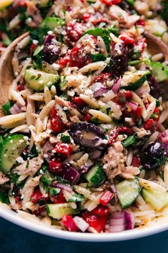 a close up of a salad in a bowl with wooden spoons on the side