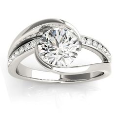 a white gold ring with diamonds on the band and a round cut diamond in the center