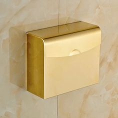 a gold toilet paper dispenser mounted on a wall with marbled background