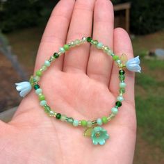 Add a touch of whimsy to your outfit with our bracelet featuring vibrant green glass beads and three dainty iridescent flowers! A stylish and practical gift for anyone who loves handmade accessories and unique fashion statements. Treat yourself or someone special today! One size fits most. Made with glass beads and plastic charms. Ships within 3-5 business days. Want a different color variation? Send us a message! We love creating custom pieces to suit your personal style. Green Bohemian Beaded Bracelets For Spring, Green Beaded Bracelets As Spring Gifts, Green Beaded Bracelets For Spring, Spring Green Adjustable Jewelry, Green Round Bead Jewelry For Spring, Green Beaded Bracelets For Spring Gifts, Green Bracelets For Spring Gift, Green Beaded Jewelry For Spring, Bohemian Green Jewelry With Flower Decoration