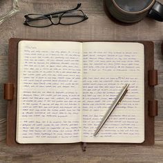 an open notebook with writing on it next to a cup of coffee and eyeglasses