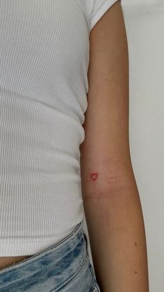 a woman with a red heart tattoo on her arm