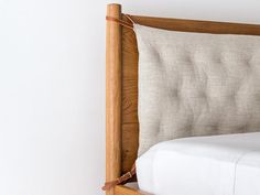 a bed with a wooden headboard and white linens on the bottom, against a wall