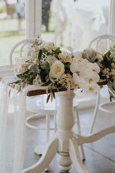 a table with white flowers and greenery on it