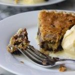 a piece of pie on a plate with ice cream and a fork in front of it