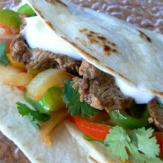 a taco filled with meat and vegetables on top of tortilla