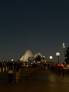 people are walking on the sidewalk at night