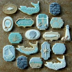 cookies decorated with blue and white icing are arranged on a counter top in the shape of seashells