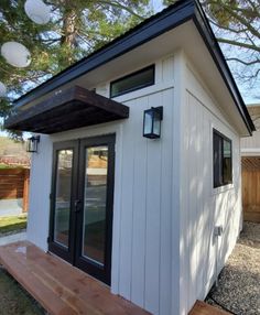 a small white building sitting in the middle of a yard