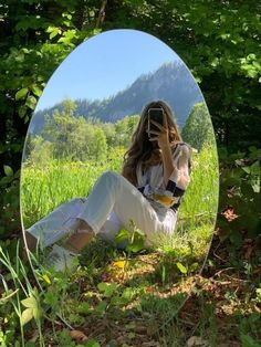 a woman sitting in the grass taking a selfie