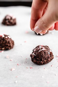 someone is picking up some chocolate cookies from the baking sheet with sprinkles