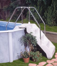 an above ground swimming pool with steps leading up to the water's edge and potted plants next to it