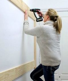 a woman is using a drill to attach the wall paneling in her home office