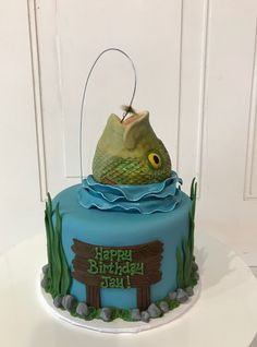 a blue birthday cake with a fish on top