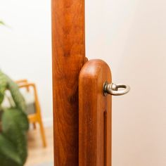 a close up of a door handle on a wooden pole with a potted plant in the background