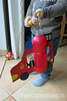 a young boy is playing with a fire hydrant made out of cardboard and construction paper