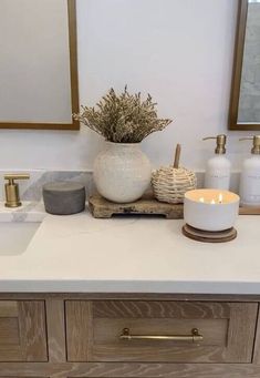 a bathroom counter with candles, soap and other items on it in front of two mirrors