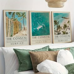 three posters on the wall above a bed in a room with white walls and green pillows