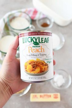 a person holding up a can of lucky leaf peach fruit filling in front of some desserts