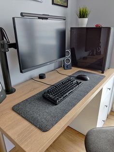 a computer desk with a keyboard, mouse and monitor on it next to a plant