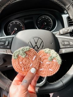 a person is holding up a crocheted flower in their car steering wheel cover