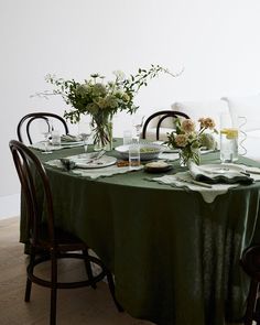 the table is set with plates and flowers in vases on it's sides