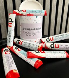 some candy sticks are sitting on top of a black table next to a cup with writing on it