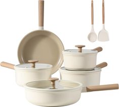 an assortment of white pots and pans with wooden spoons on the top one