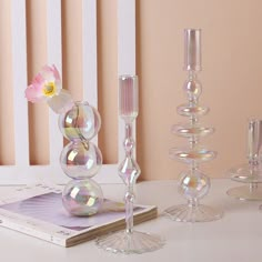 there are many glass vases and candles on the table with pink flowers in them