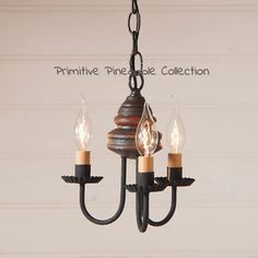 a chandelier with three lit candles hanging from it's center and the words primitive pine candle collection written above it