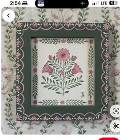 the frame is decorated with pink flowers and green leaves on a white fabric wallpaper